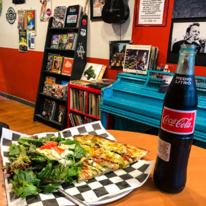 A slice of pizza and a Coke on a table