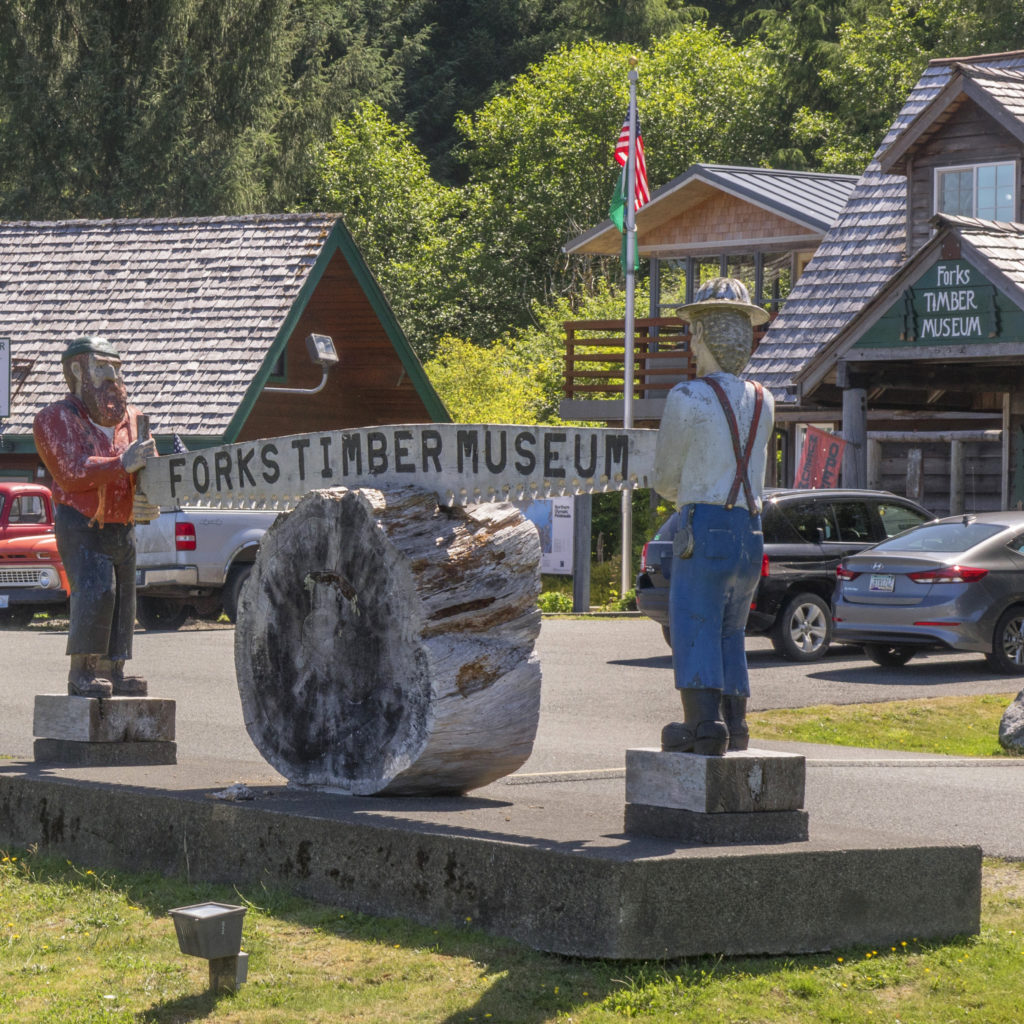 A statue of two loggers with a saw in front of the Forks Timber Museum