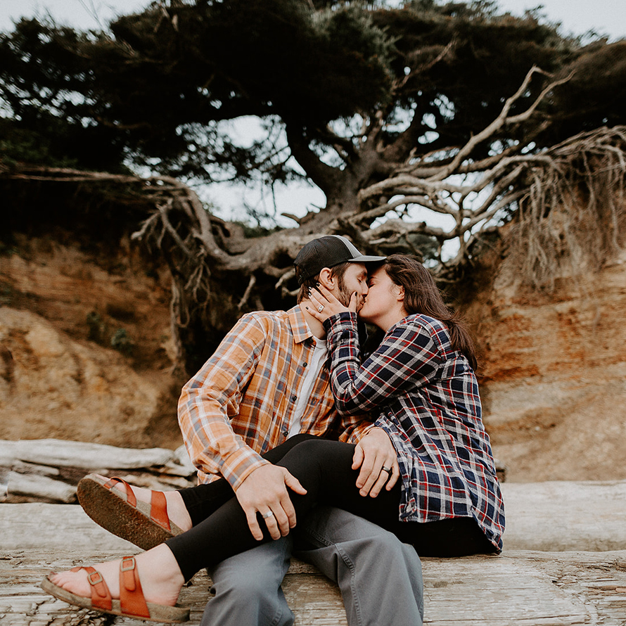 A couple kisses in front of the Tree of Life at Kalaloch