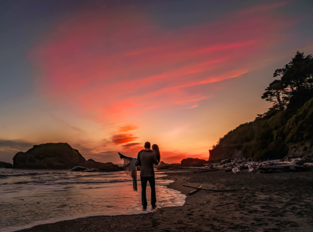 A couple on the beach at sunset with a heart-shaped cloud