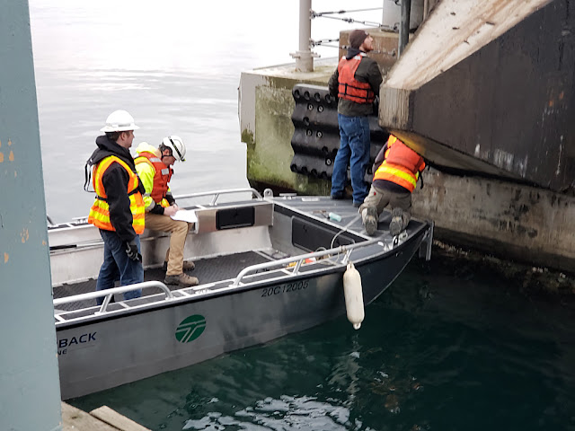 Workers in a boat inspecting the internal lock system of the Hood Canal Bridge