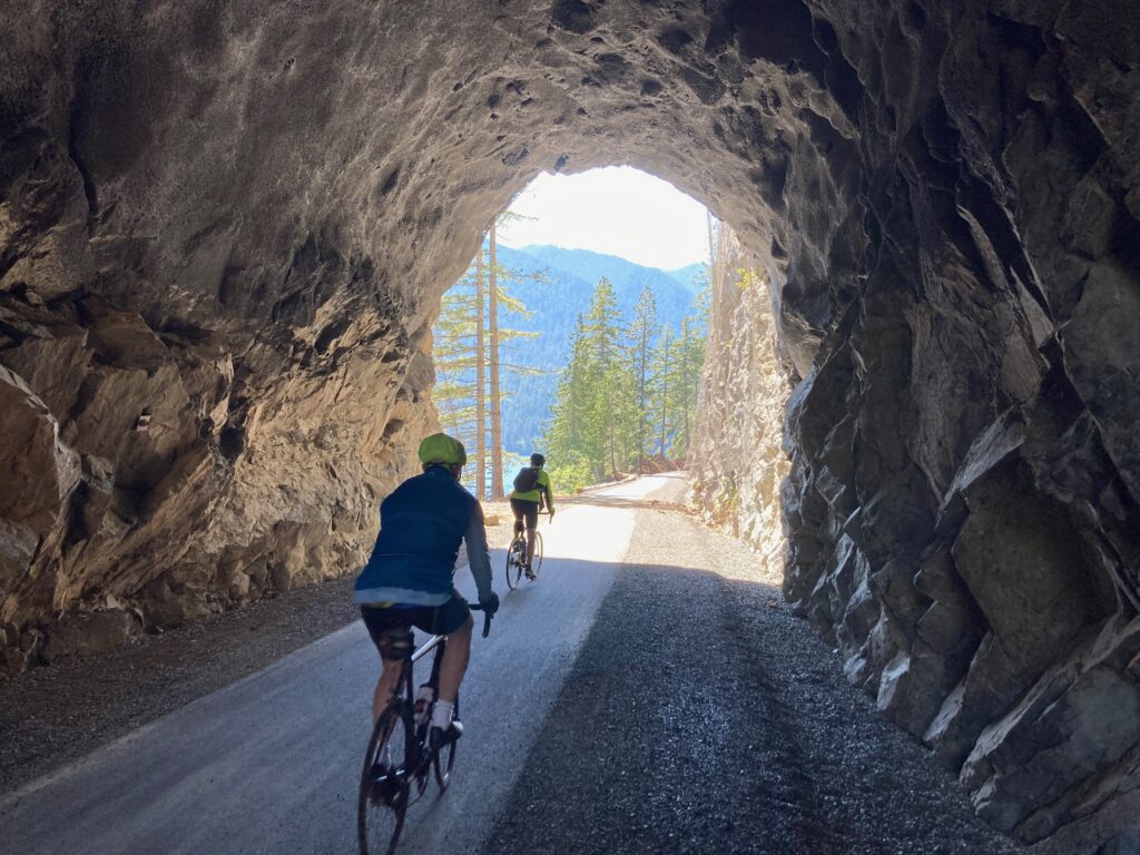 Photo of bicyclists riding their bikes through mountain tunnel on the Olympic Discovery Trail. 