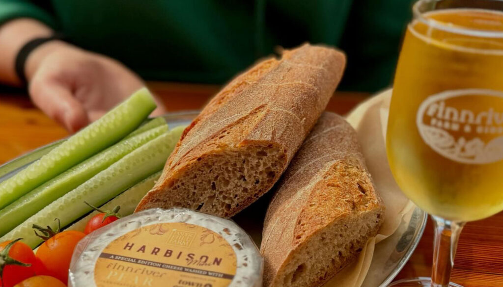 A selection of local food at Finnriver including a glass of hard cider, fresh baked bread and local cheese 