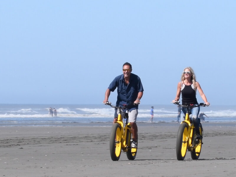 Couples Ride Bicyles on the beach in Ocean Shores