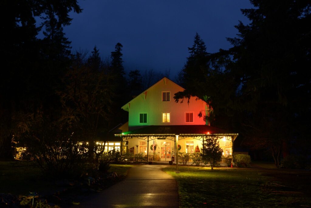 Photo of Lake Crescent Lodge lit up with green and red lights at night.
