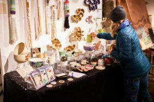 Photo of a shopper perusing a vendor table at the 2024 Wintertide Makers Market in Port Angeles, WA