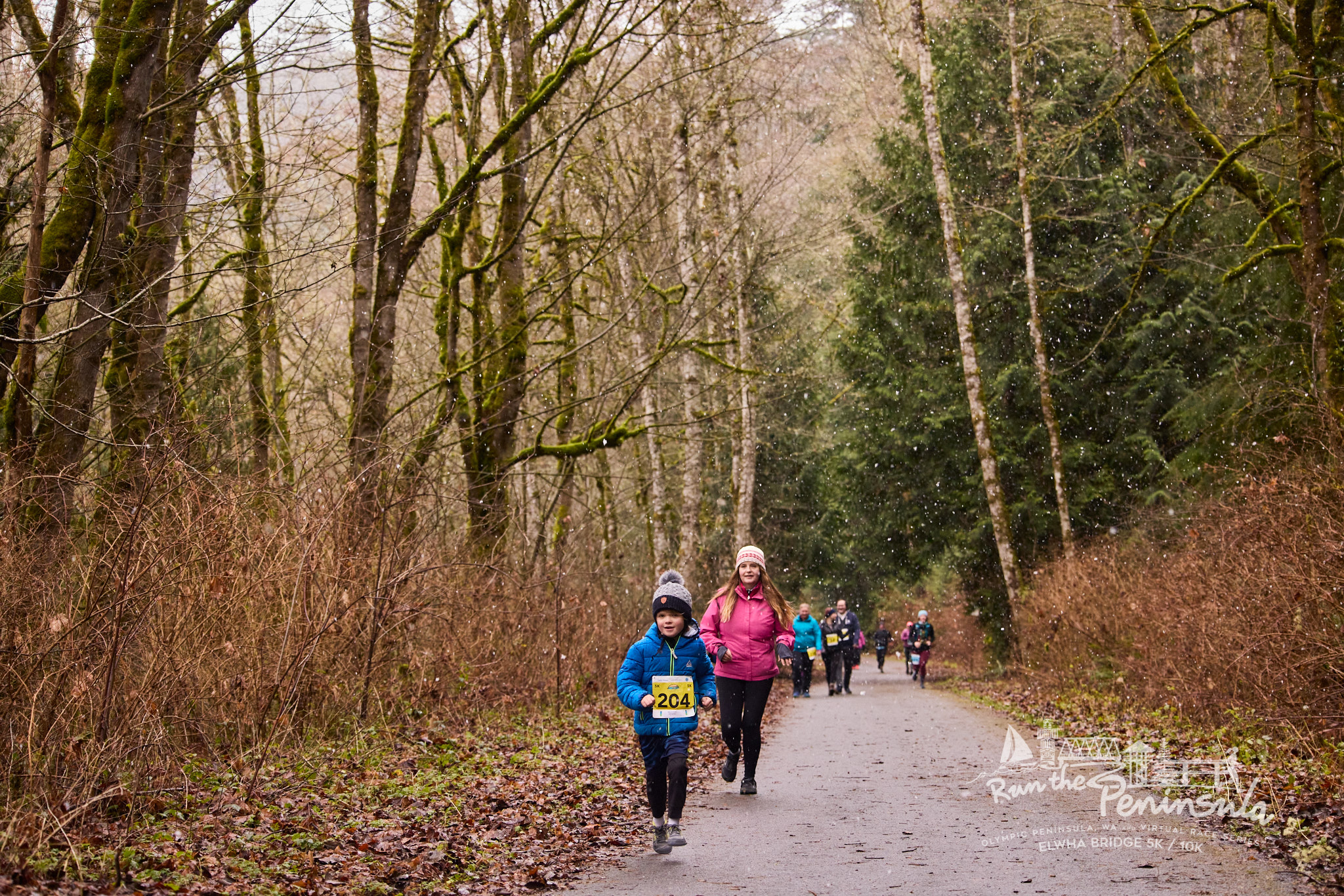 Run The Peninsula Race Series Elwha Bridge Run participants running in the forest on a trail