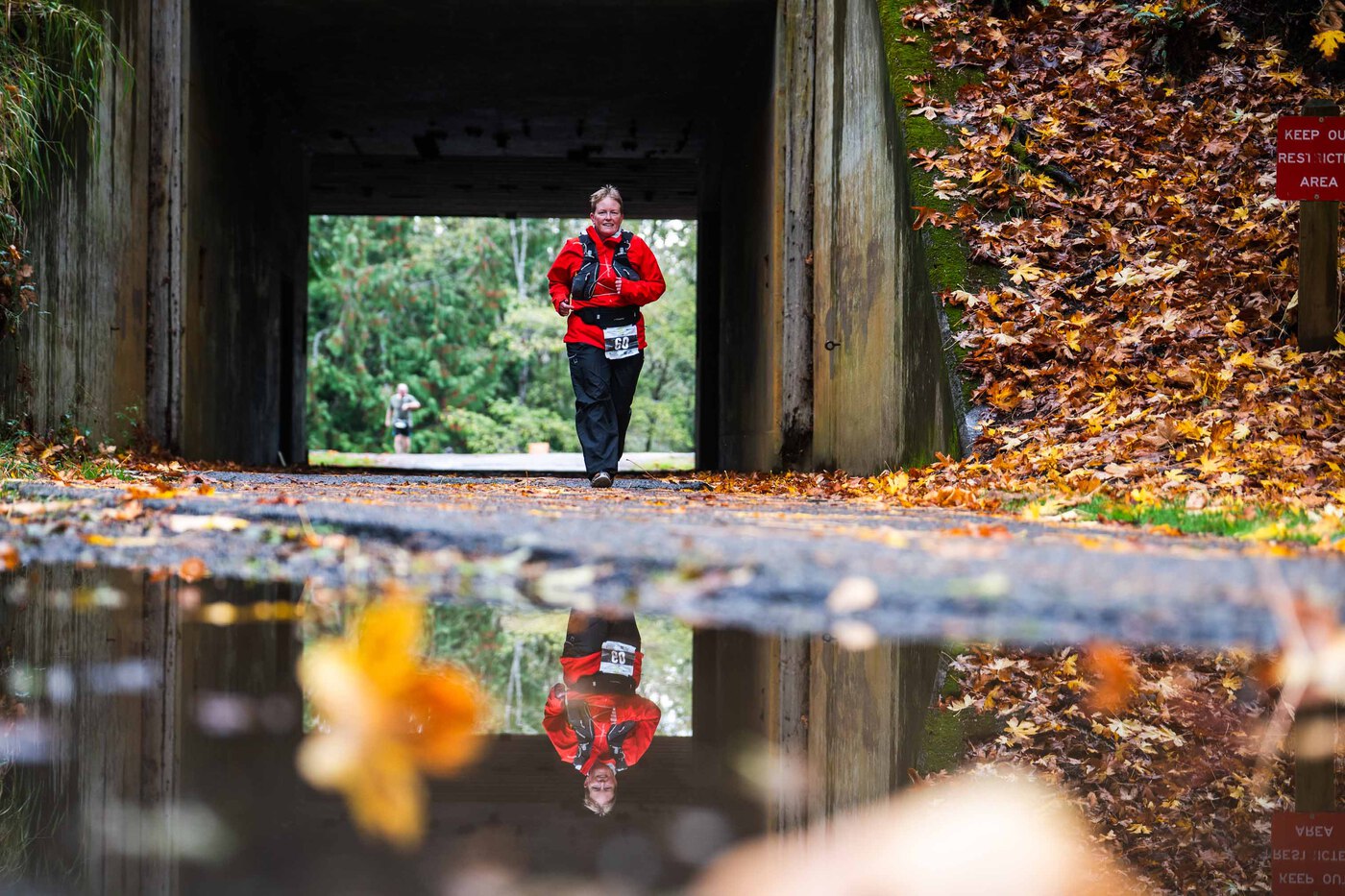 Photo of runner running underneath  a bridge on a trail in the forest during the Salt Creek 24 race